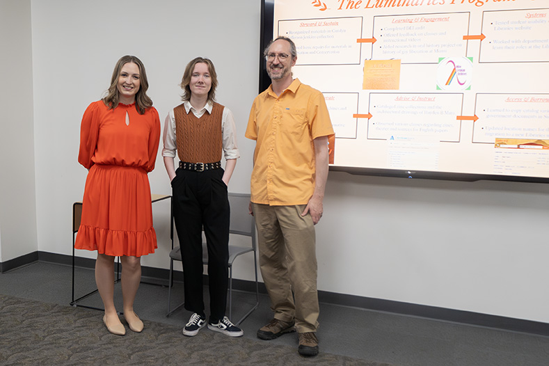 Marlow Zuch stands between Laura Burkenhauer and Ken Irwin during their poster presentation. 